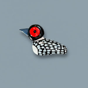 Decorative bird-shaped object with a red eye on a textured black surface