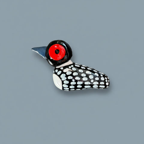 Decorative bird-shaped object with a red eye on a textured black surface
